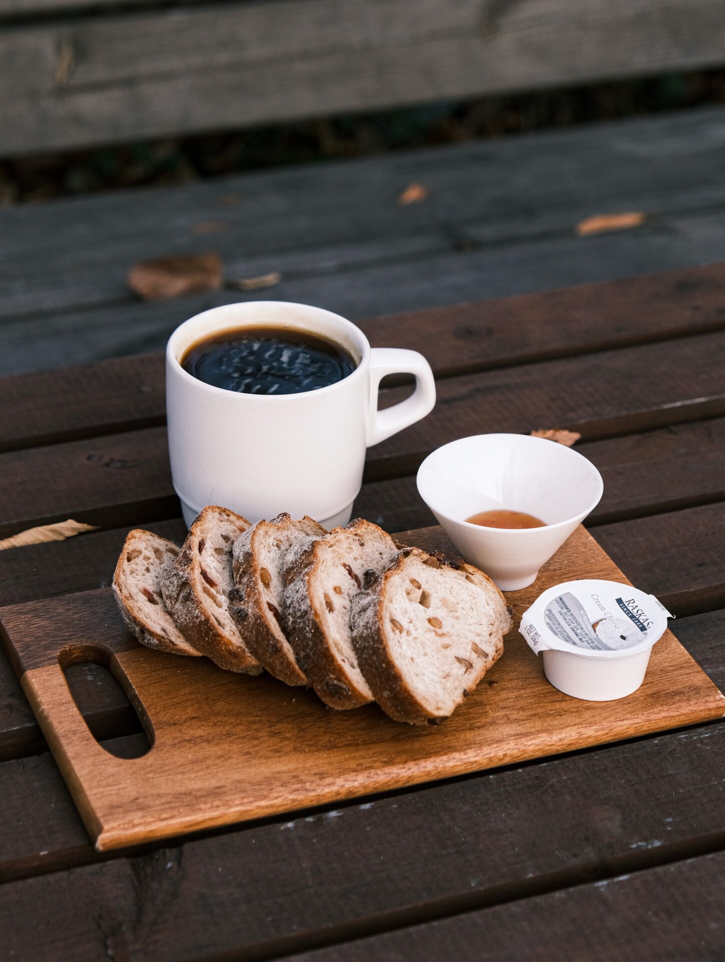 bread-and-coffee-scaled-1 A cup of coffee, cream, and several slices of bread are displayed on a wooden serving tray