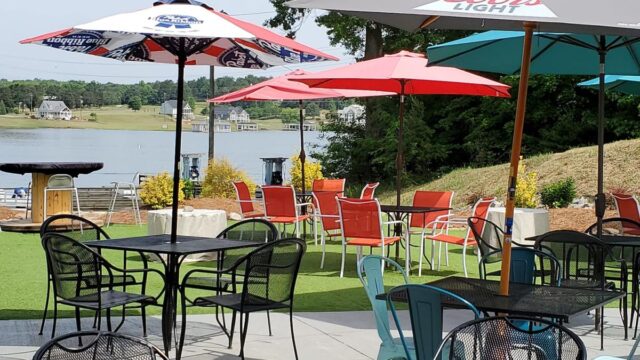 An outdoor patio at a restaurant with black metal tables and chairs with colorful shade umbrellas
