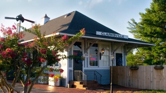 Exterior of a light blue clapboard building with brick steps leading up to the front door