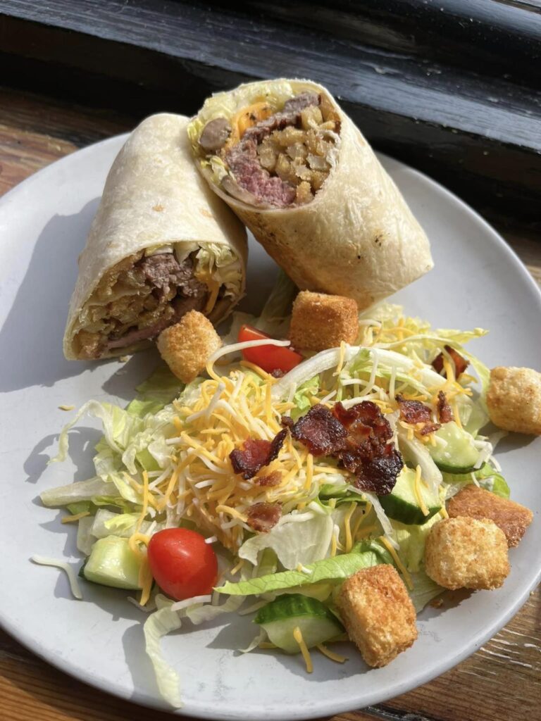 A round white plate with a burrito sliced in half and a salad