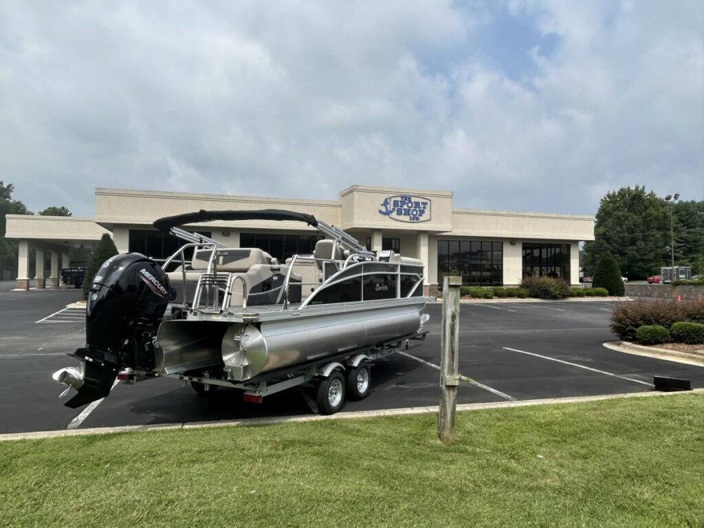 A motorboat sits on wheels in a parking lot outside a sport shop