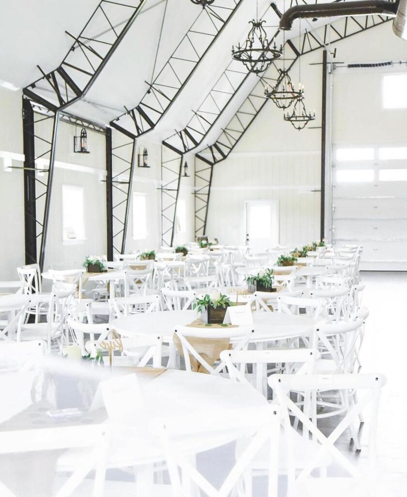 A white indoors event space with white tables and chairs